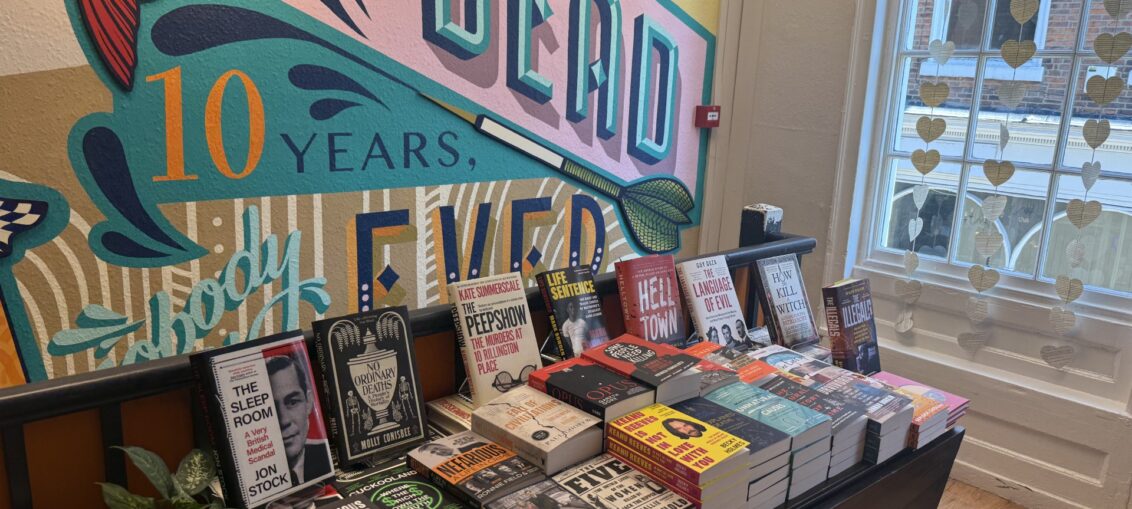 A display of Books, and a wall mural at Criminally Good Books