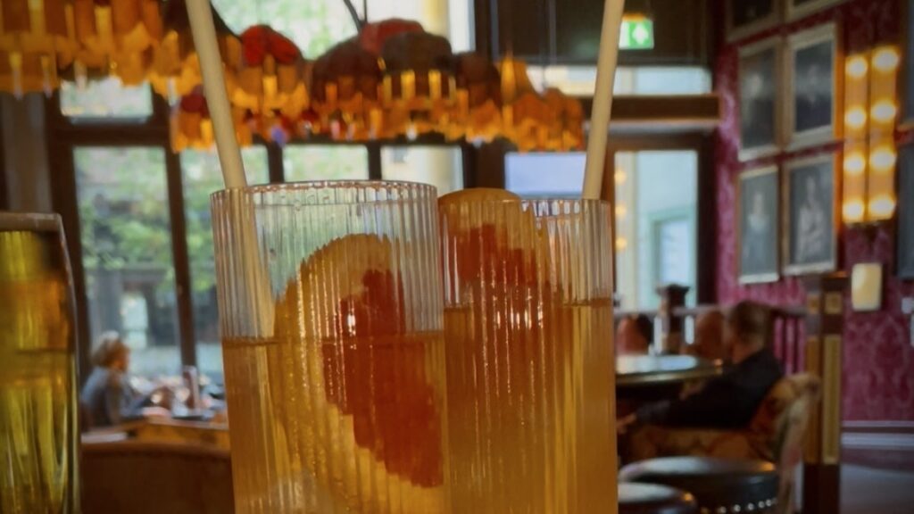 Two cocktails with grapefruit slices in them and the cosy club in the background.